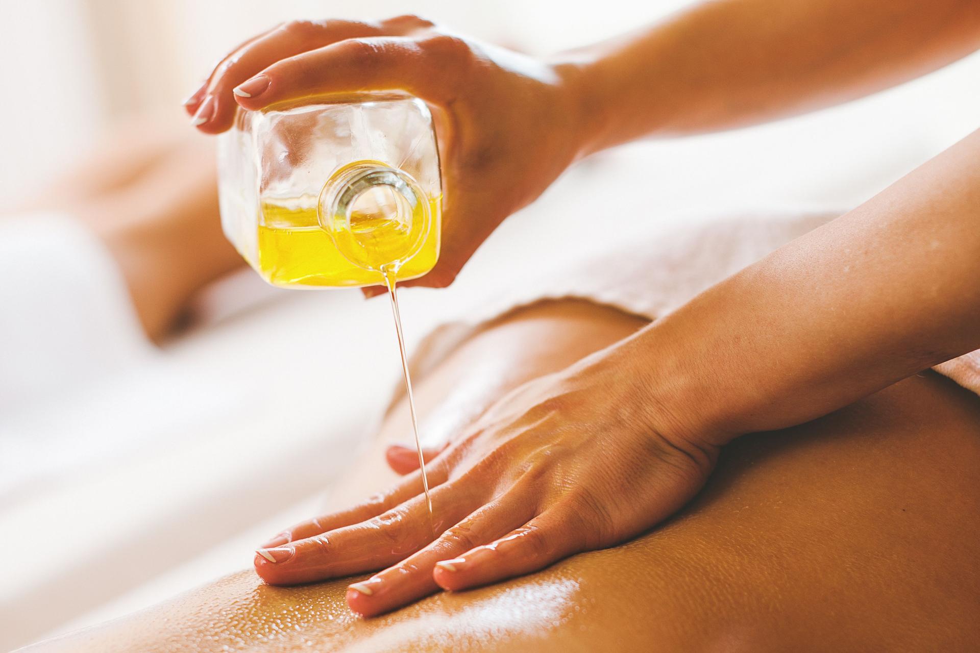 Woman pouring massage oil on spa client