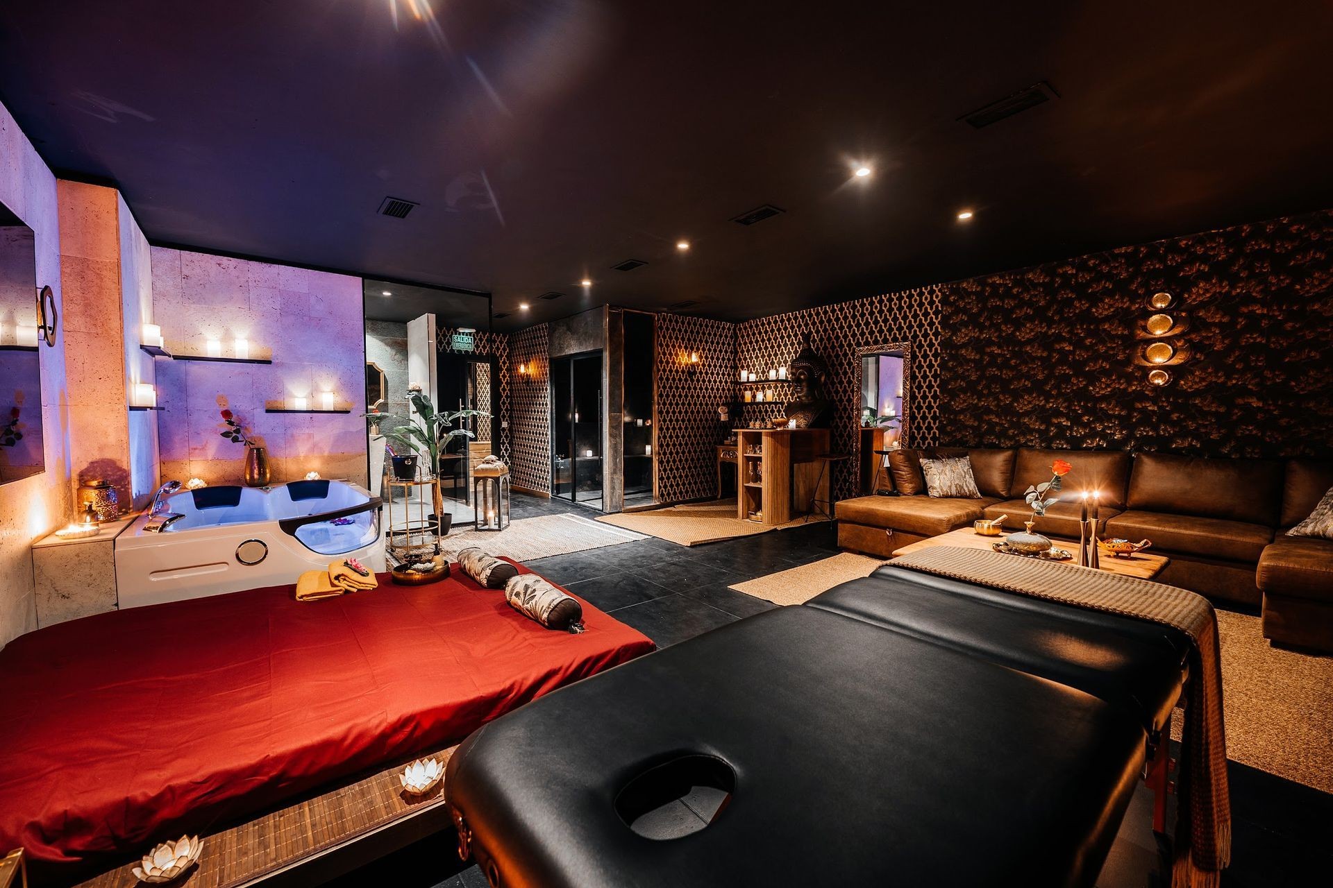 Luxurious spa room with massage tables, jacuzzi, candles, and elegant decor in warm lighting.