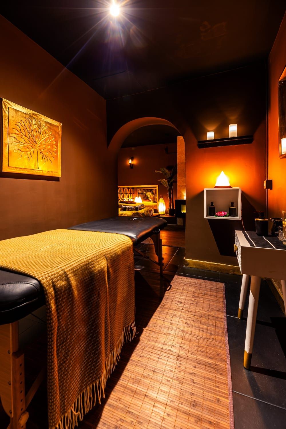 Cozy massage room with a table, warm lighting, and decorative art on the walls.