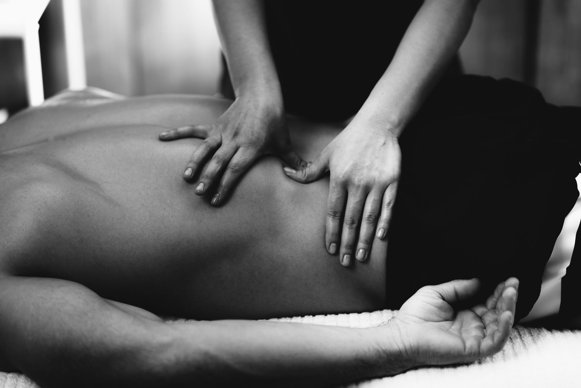 Physiotherapist massaging male patient with injured lower back muscle. Sports injury treatment.